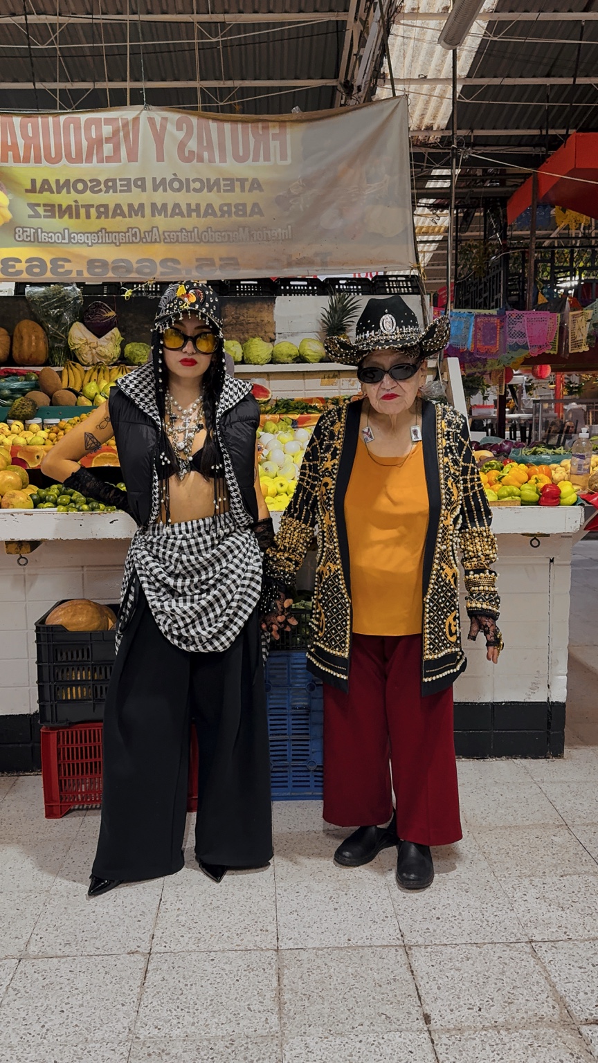Dixy y su abuela juntas frente al puesto de frutas del Mercado Juárez