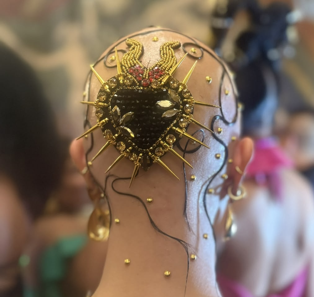 Detalle de tocado dorado con corazón en backstage.