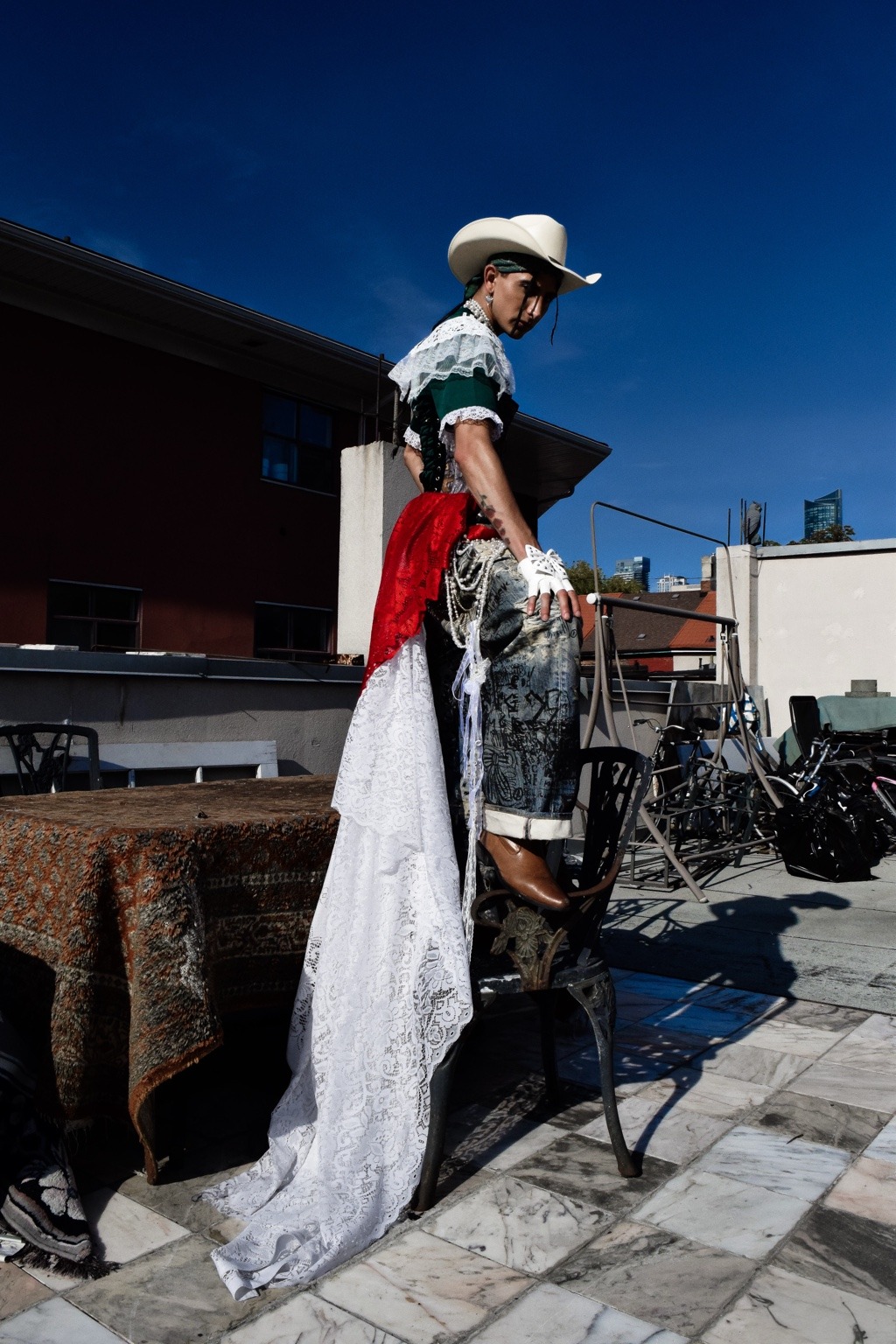 Modelo con sombrero blanco y una larga cola de encaje en una terraza.