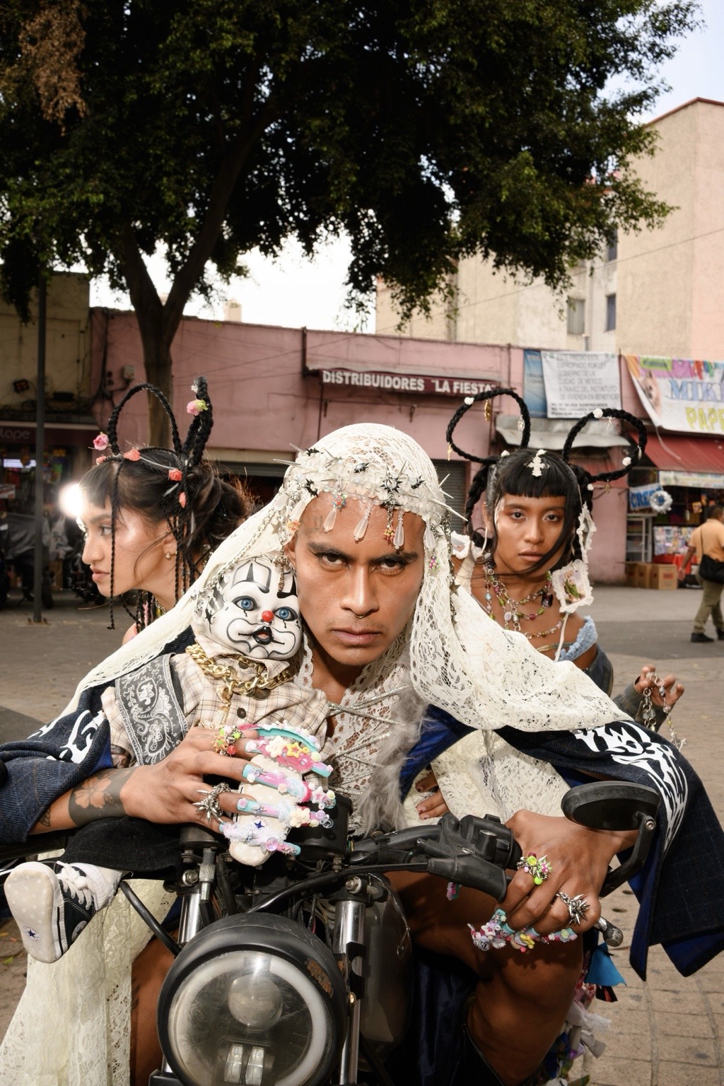 Retrato de tres modelos sobre una motocicleta, con velo blanco, trenzas y joyería en La Merced.