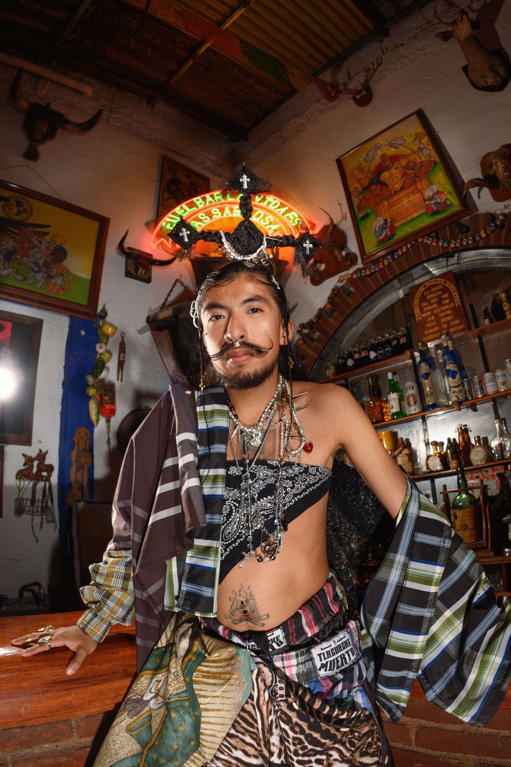 Modelo con pañuelo de cuadros, estampado animal y joyería frente a la barra.