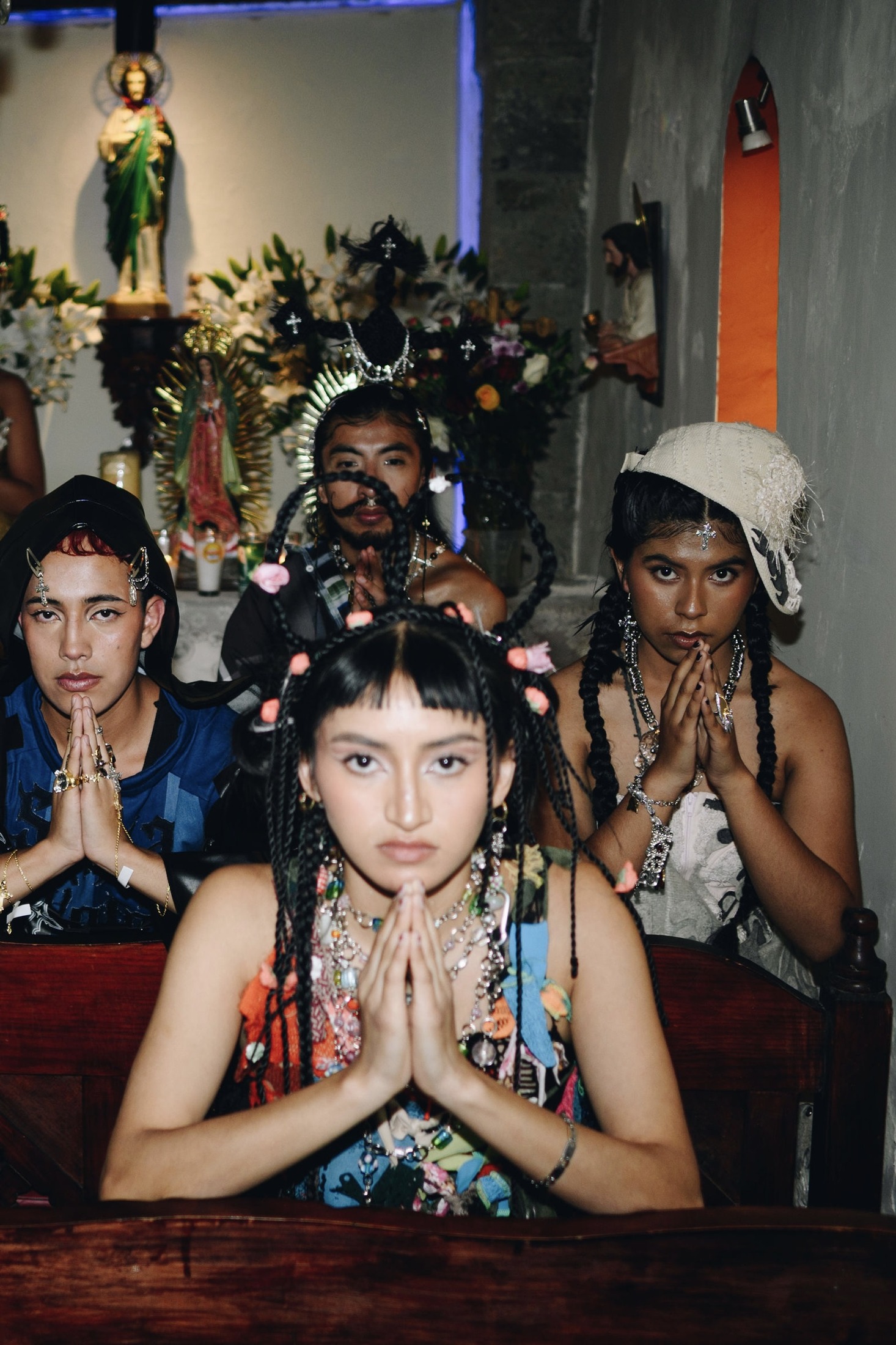 Cuatro modelos con las manos juntas y joyería, frente al altar.
